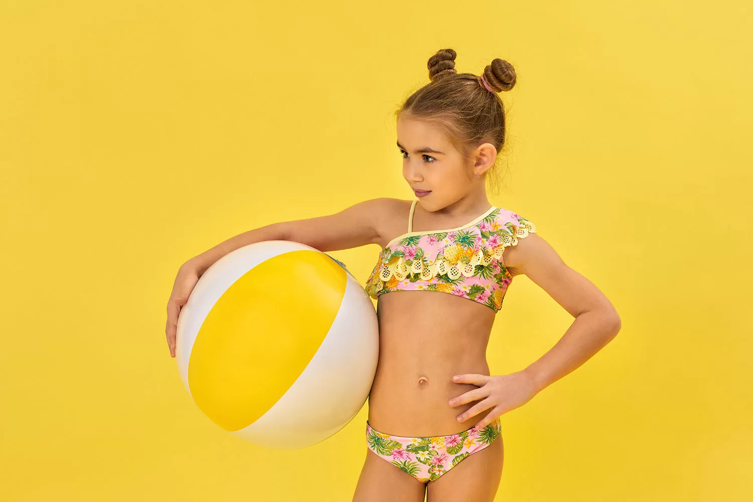 cute little child girl in swimwear with beach ball on yellow background